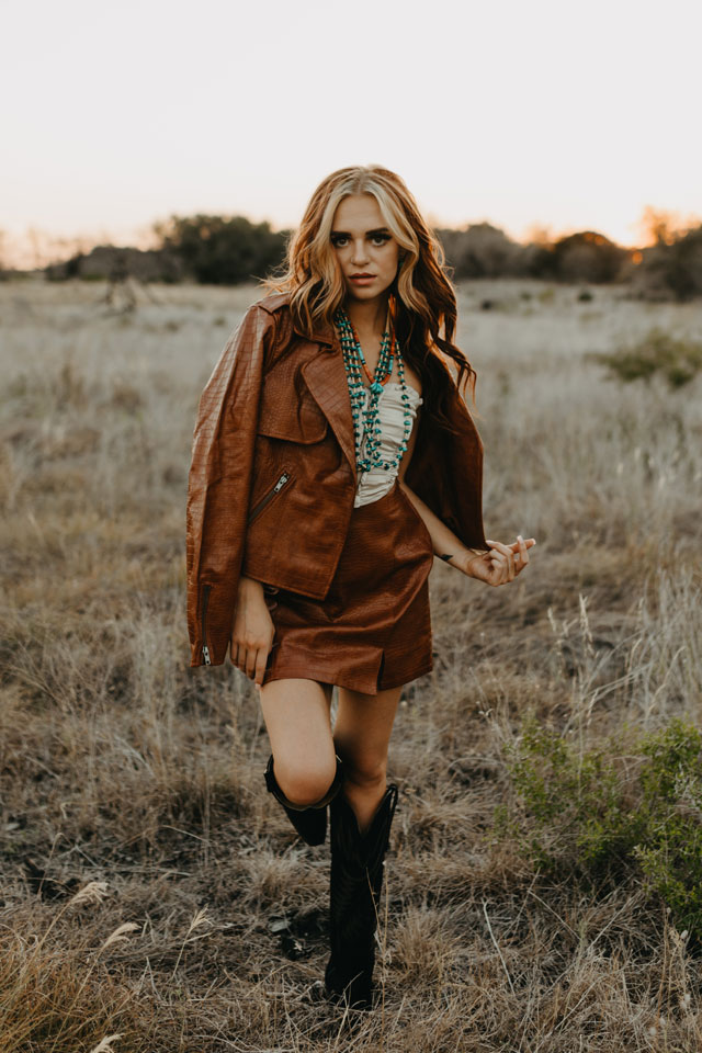 A woman standing in a field wearing Justin Boots.